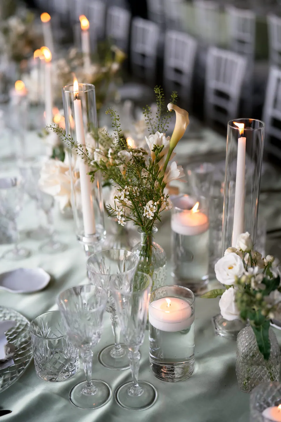 Table with candles, crystal glasses and white flowers.