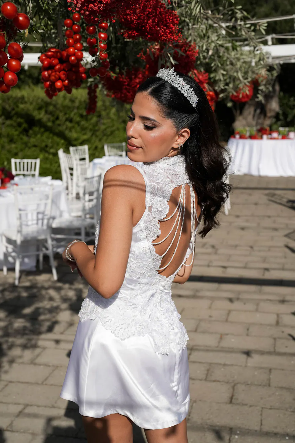 Le dos de la robe de fête, des rangs de perles sur les épaules, sous les tomates suspendues.