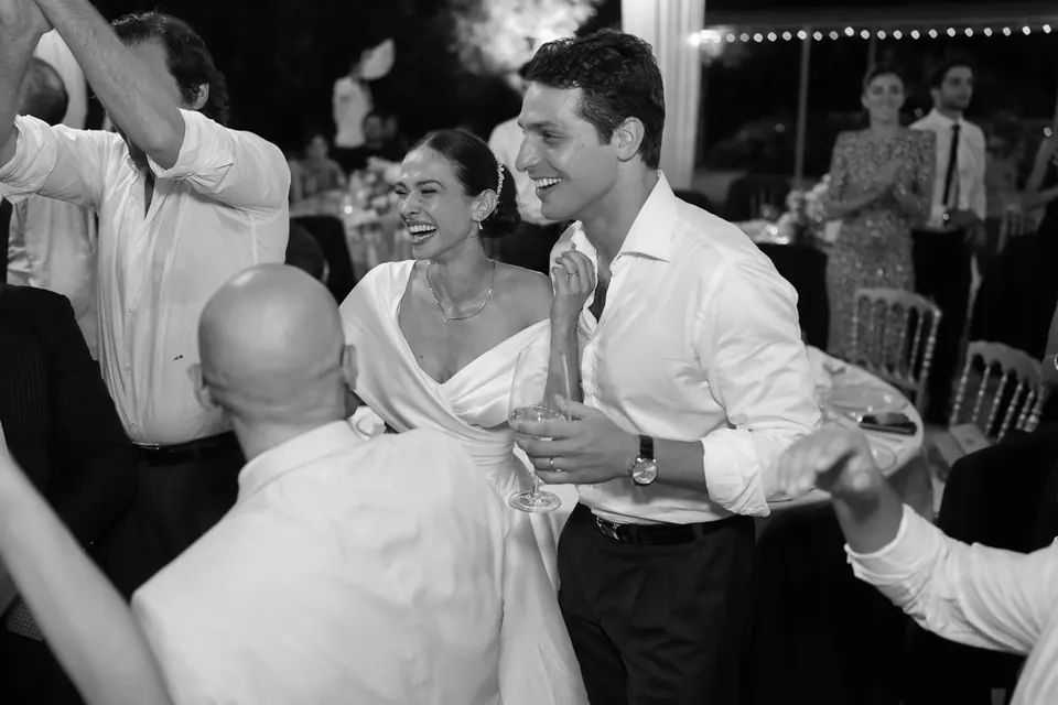 Foto in bianco e nero degli sposi che ballano tra gli amici alla festa.