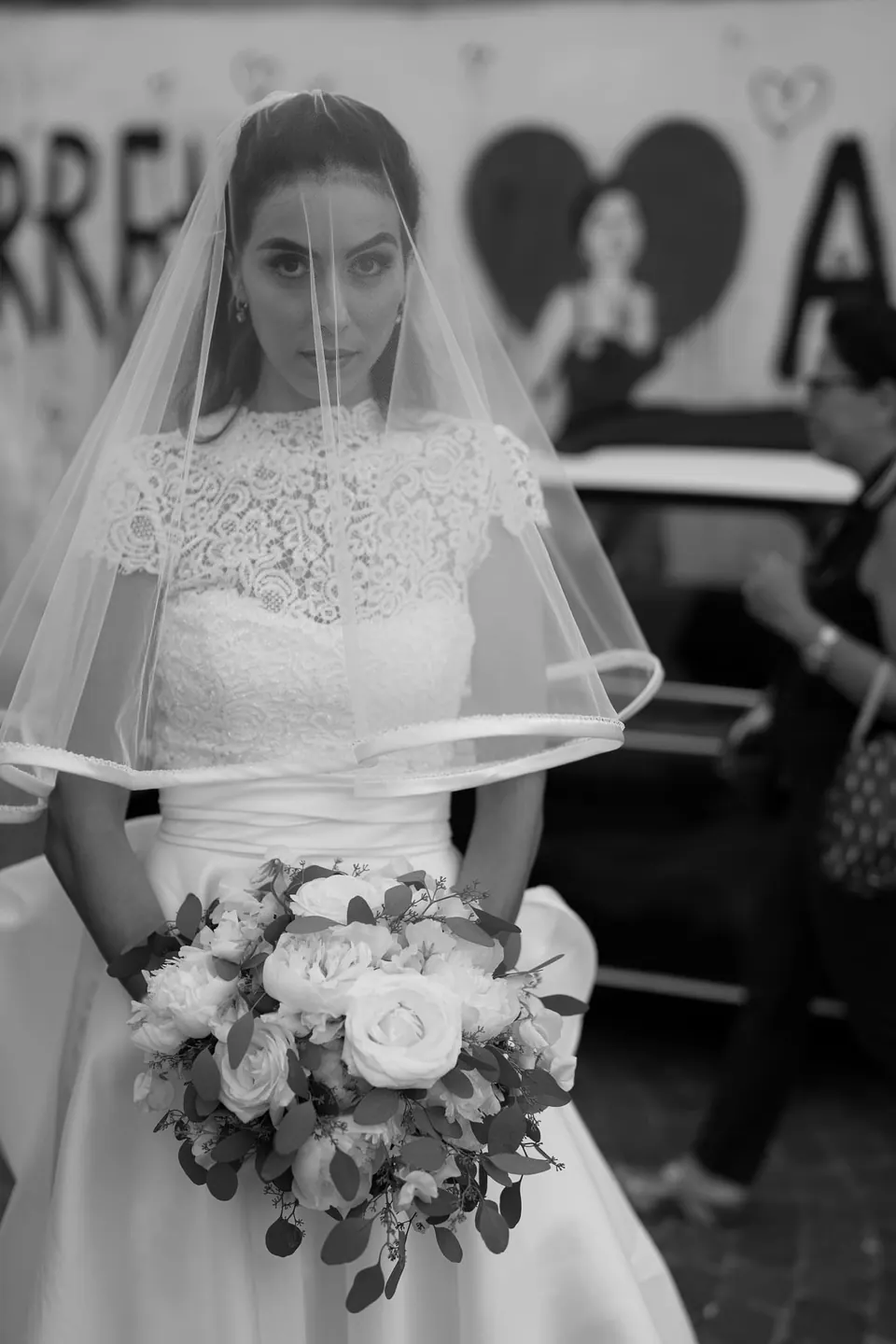 Bride in her veil holding her bouquet in the street