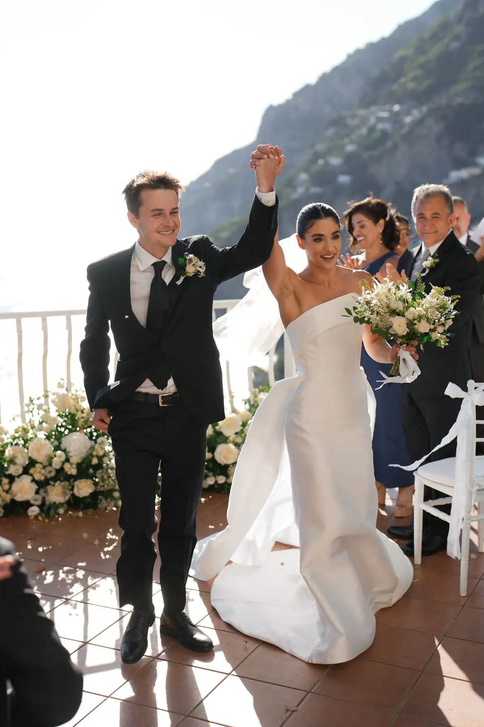 Groom raising his arm as the newlyweds walk back up the aisle.