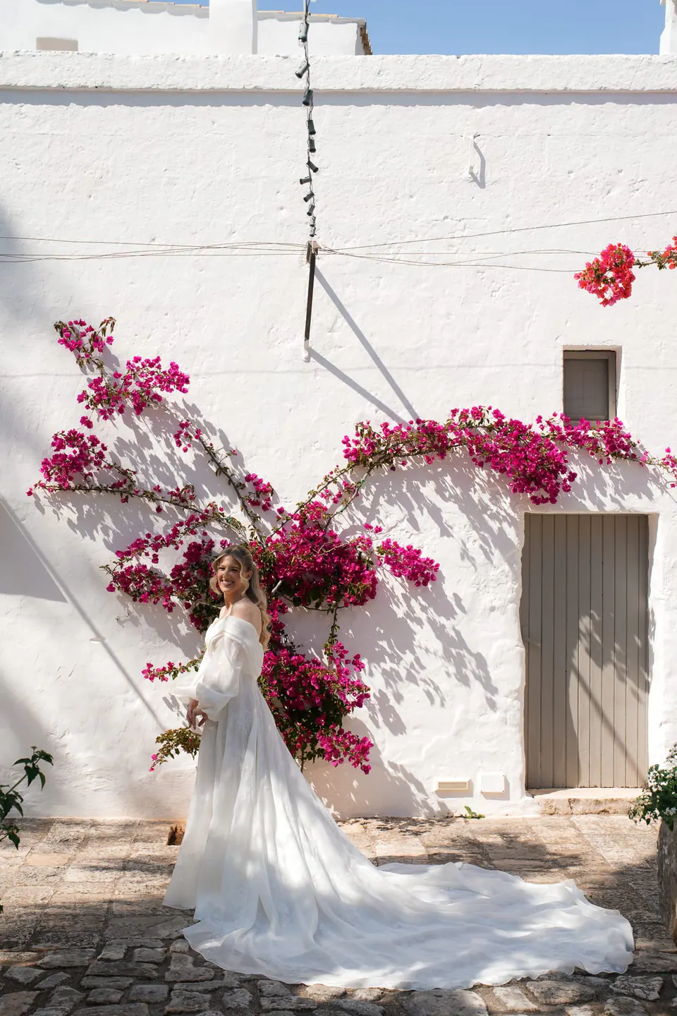 La novia bajo un arco de buganvillas rojas.