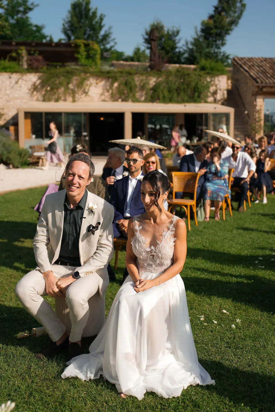 Bride seated beside an older man in the front row on the lawn
