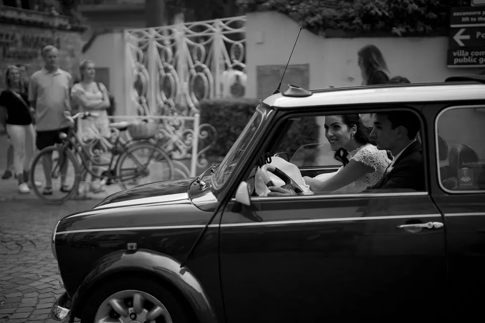 Black and white photo of bride and groom smiling in a vintage Mini