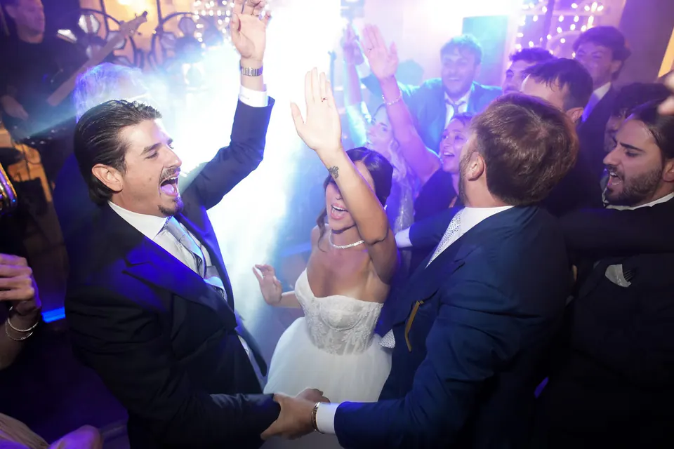 The groom dancing with friends under coloured lights