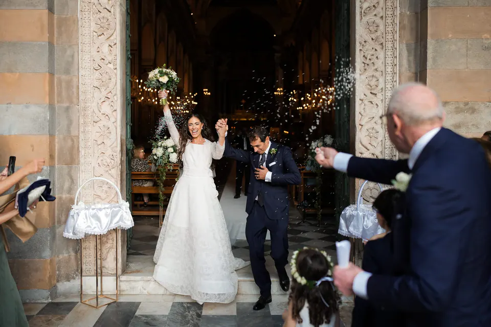Bride and groom leaving the Duomo di Amalfi as guests throw rice.