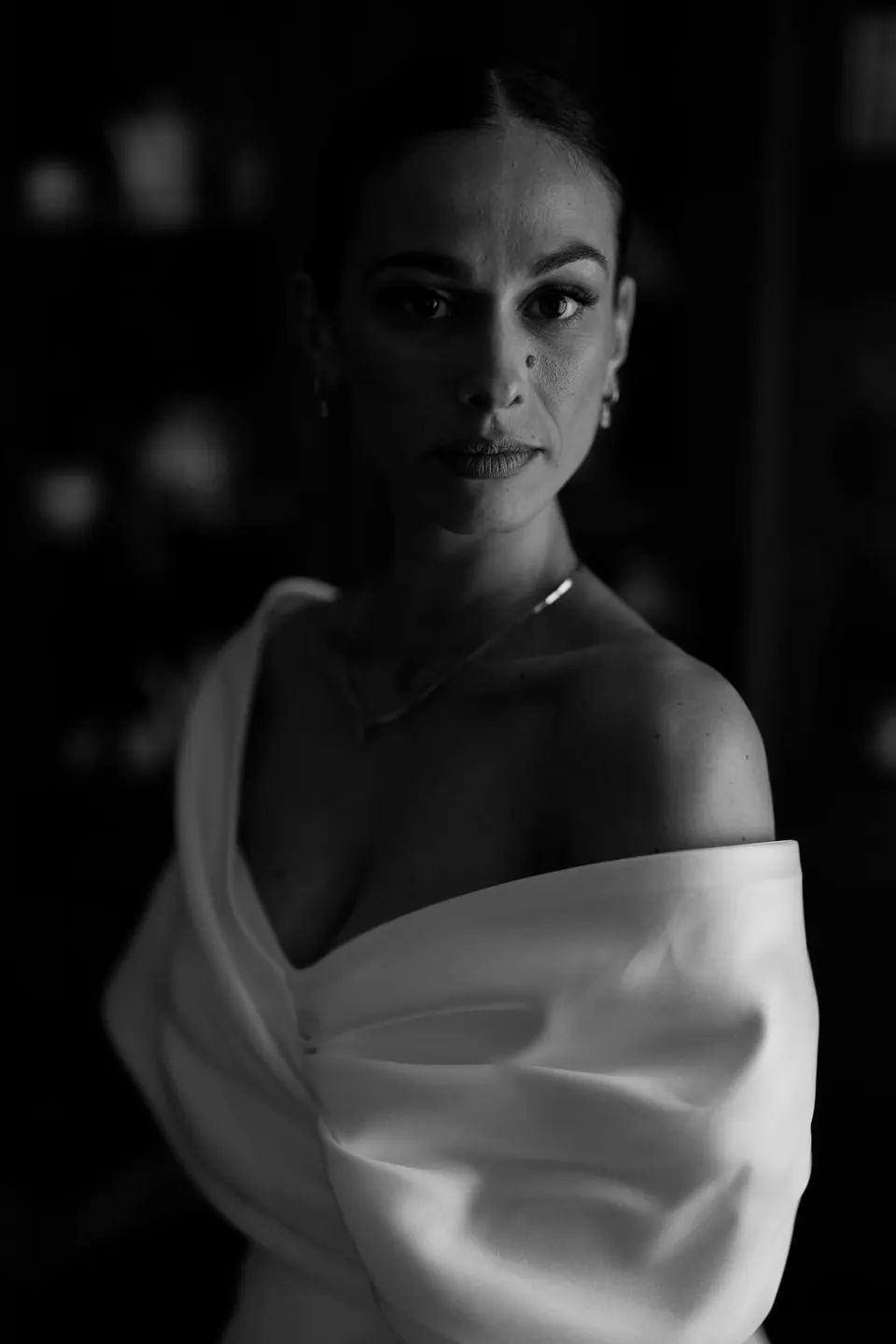Ritratto in bianco e nero della sposa con l'abito a spalle scoperte, luce drammatica.
