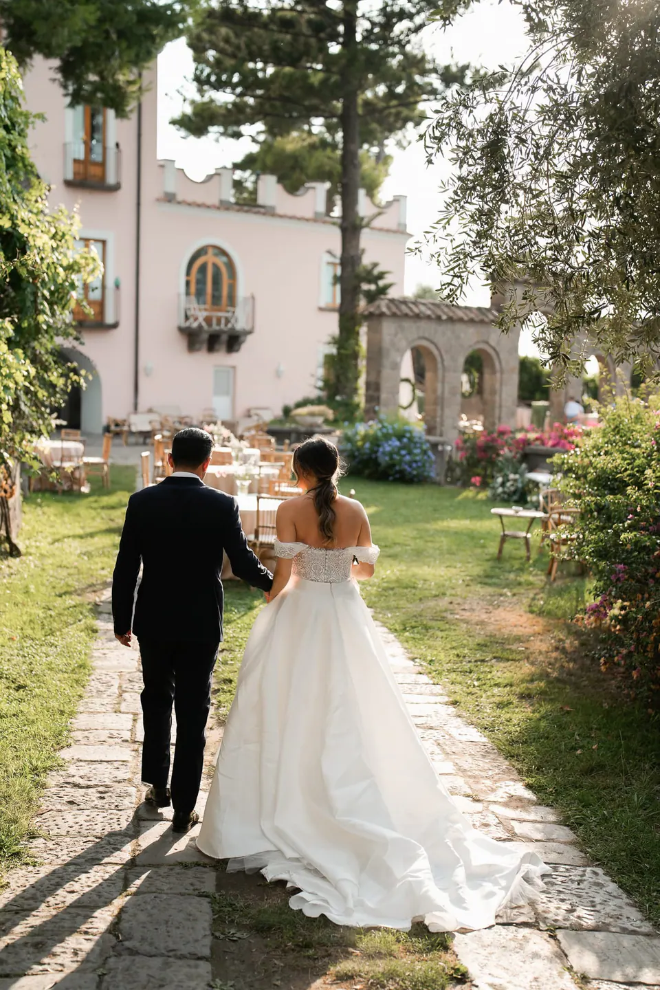 Bride and groom walking up the garden path towards the villa