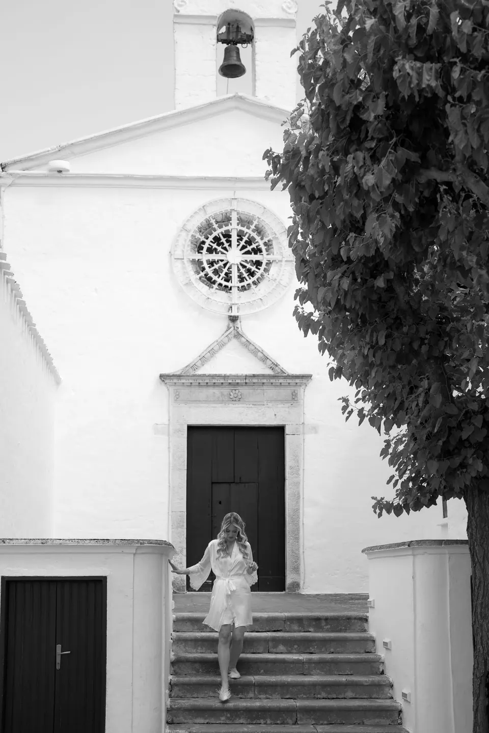 La novia baja los escalones de una pequeña capilla blanca.