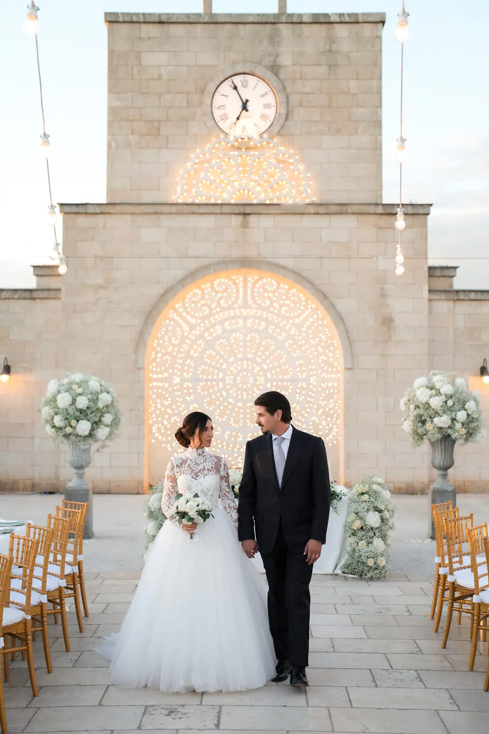 Bride and groom in the courtyard under the clock tower of Tenuta San Domenico