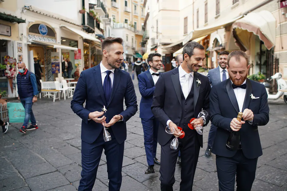 Groomsmen walking through the streets of Amalfi, drinks in hand.