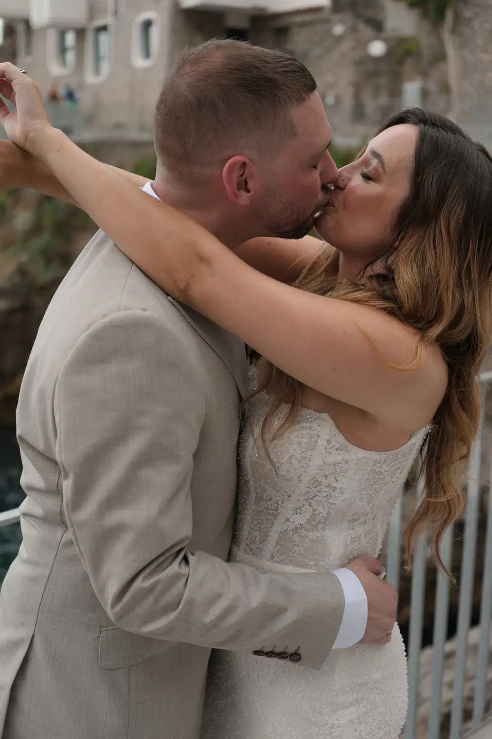 Couple kissing and embracing by the sea, the cliffs of the coast behind.