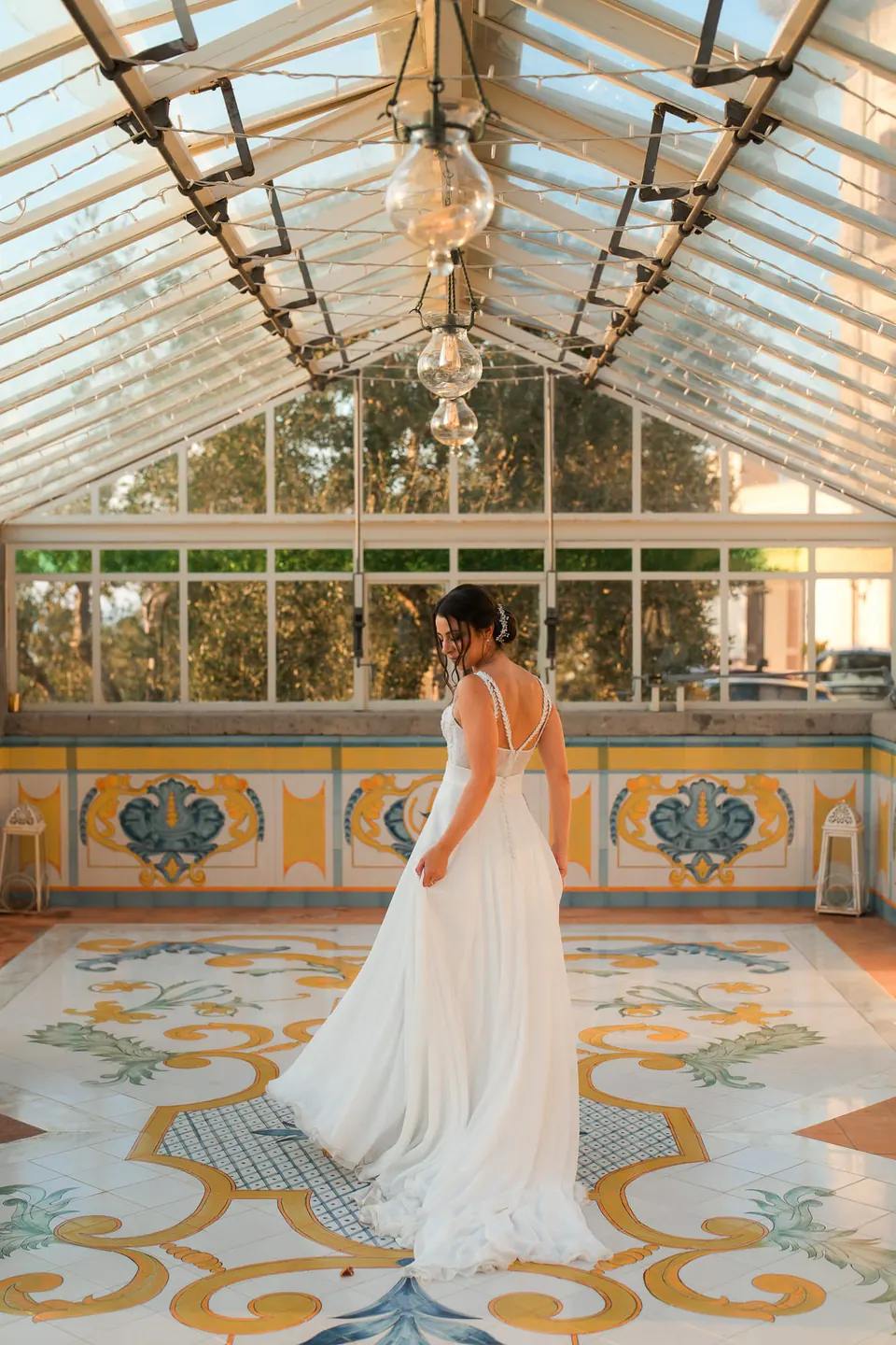 Bride under the glass dome of Villa Angelina, golden light on her gown.
