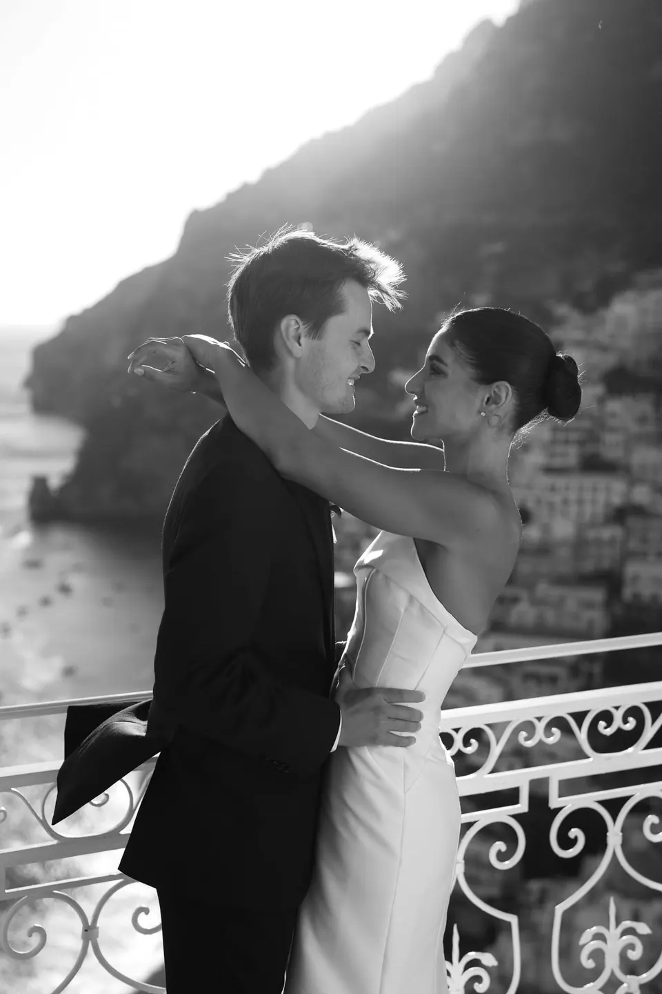 Black and white photo of the couple embracing at the railing.