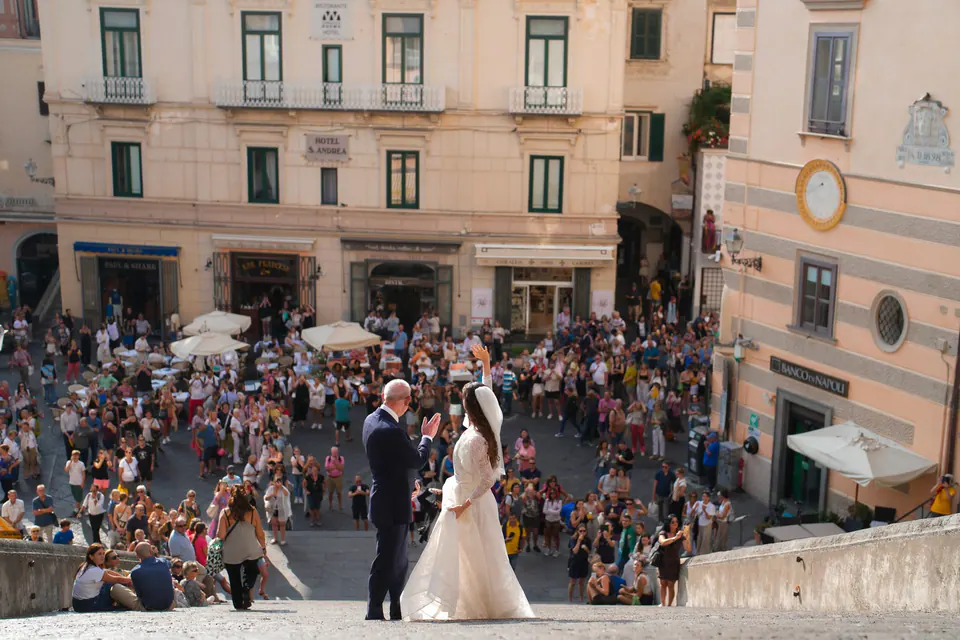 Bride and groom in Piazza Duomo in Amalfi, surrounded by guests and onlookers.