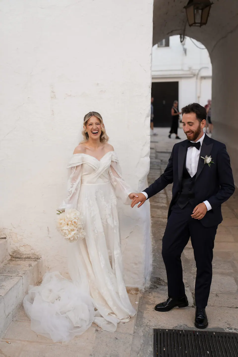 Couple standing before whitewashed walls, romantic Southern Italy destination wedding.