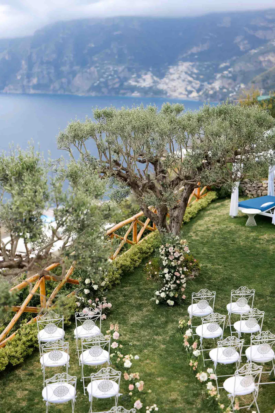 Allestimento della cerimonia con vista sul mare di Amalfi, sedie bianche e ulivi che incorniciano il romantico panorama.