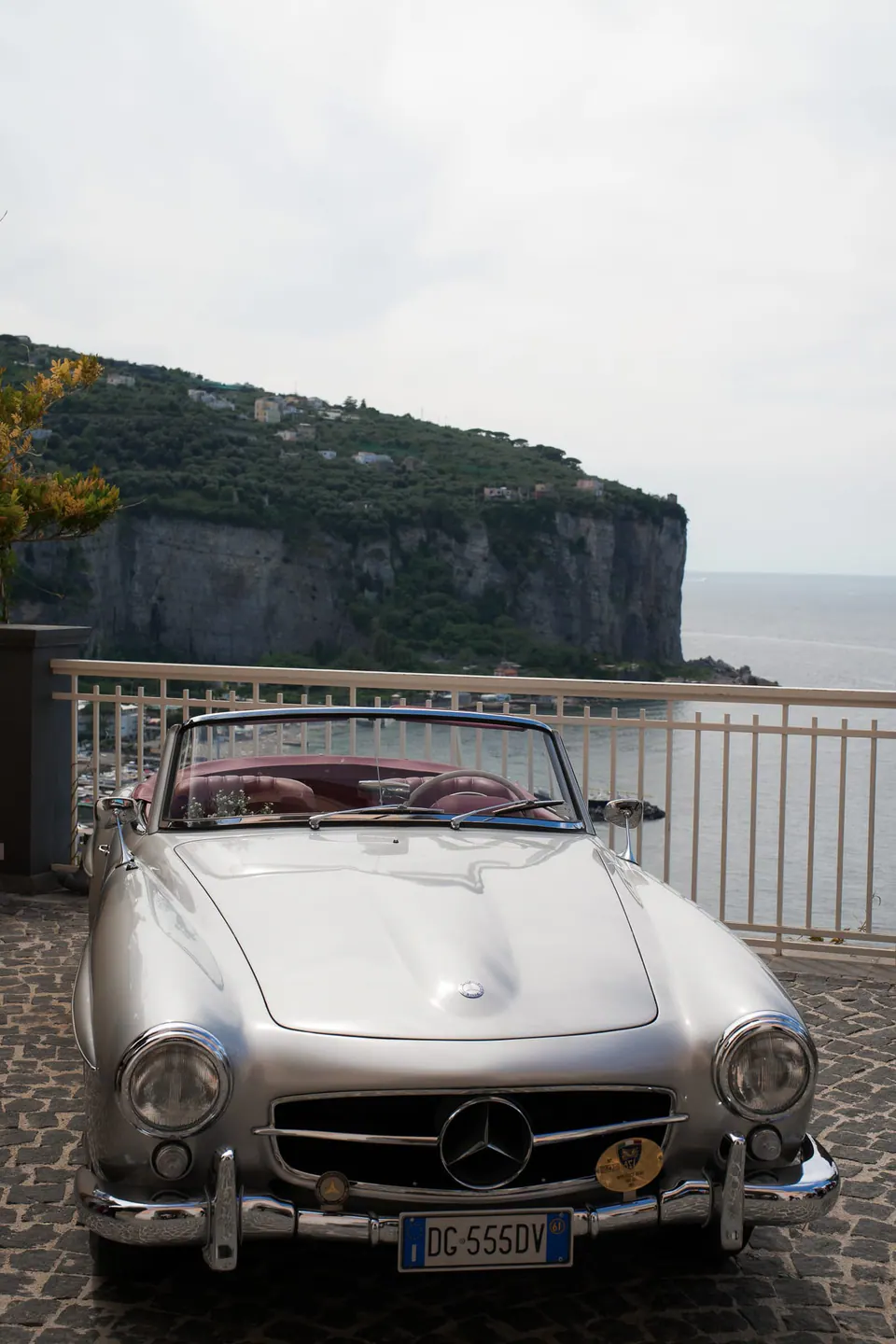 Silbernes Mercedes-Oldtimer-Cabrio auf der Klippenterrasse über dem Meer.