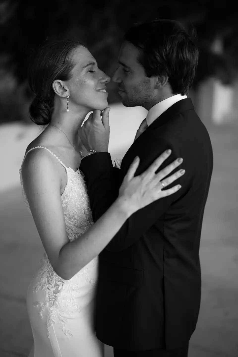 Black and white portrait of the couple kissing, his hand on her face.