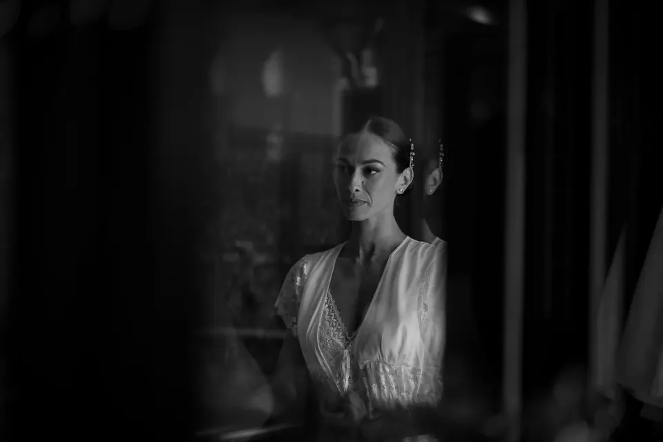 Foto in bianco e nero della sposa riflessa in una stanza buia.