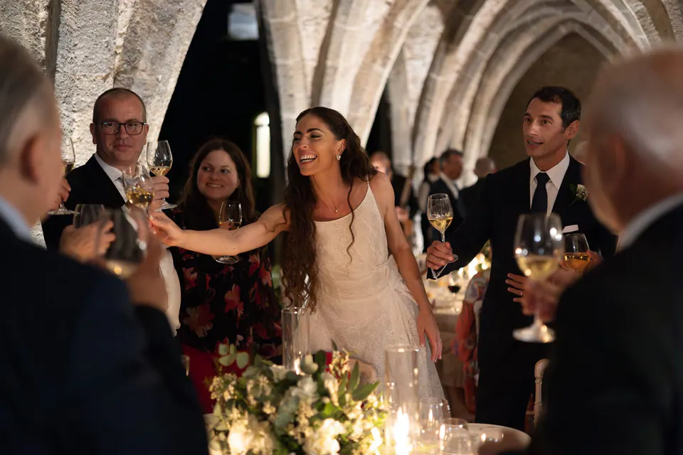Bride toasting with her guests at dinner in the crypt of Villa Cimbrone.