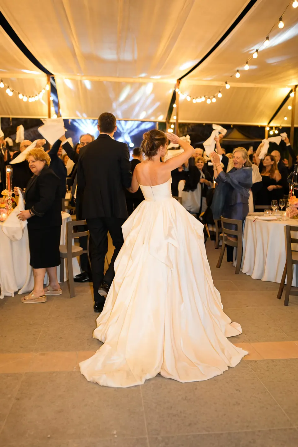 La sposa balla sotto la tensostruttura bianca tra gli invitati che la acclamano.