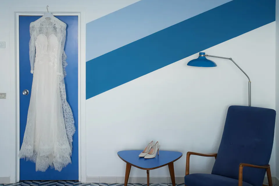 Kleid und Schuhe der Braut vor einer blau gestreiften Wand, Detail im Parco dei Principi.