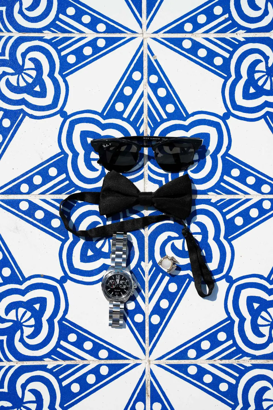 Fliege, Manschettenknöpfe und Uhr des Bräutigams auf blau-weißen Majolikafliesen, Detail einer Hochzeit in Castellabate.