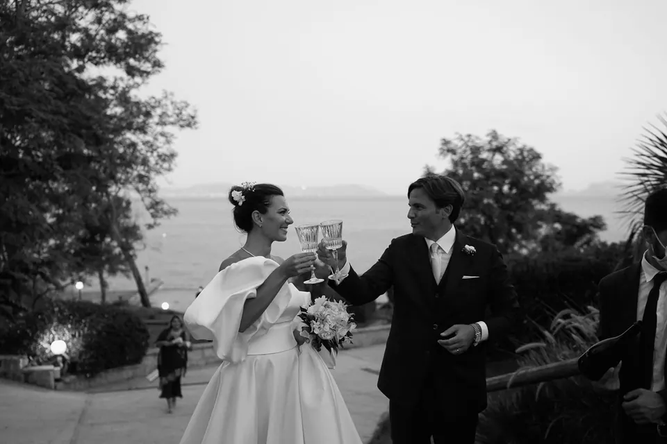 Black and white photo of the couple celebrating in the garden above the sea at dusk.