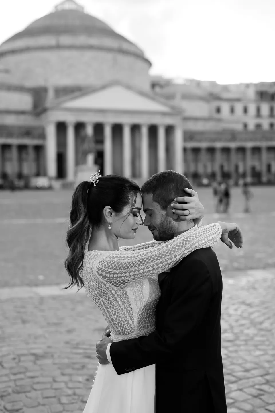 Black and white photo of the couple embracing in Piazza del Plebiscito.