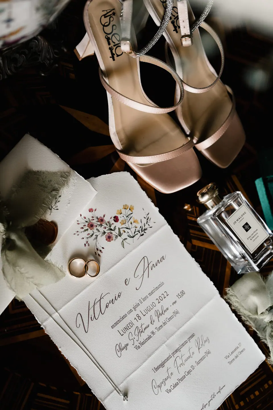 Wedding stationery, rings and bridal shoes in warm tones.