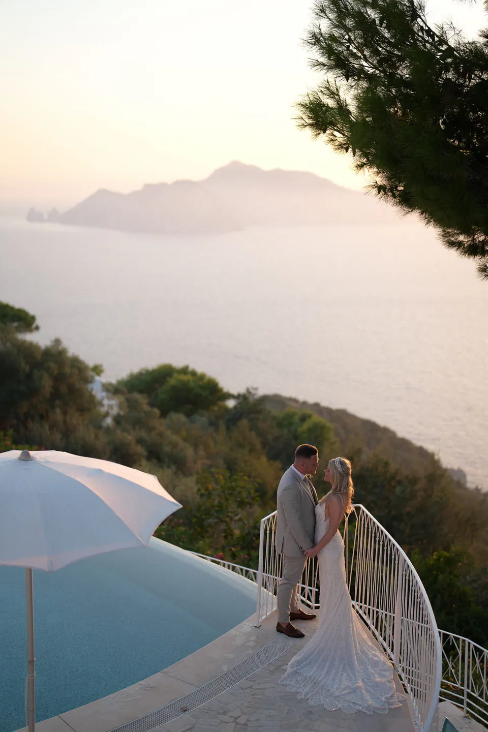Bride and groom at the pool terrace of Relais Blu, Capri on the horizon