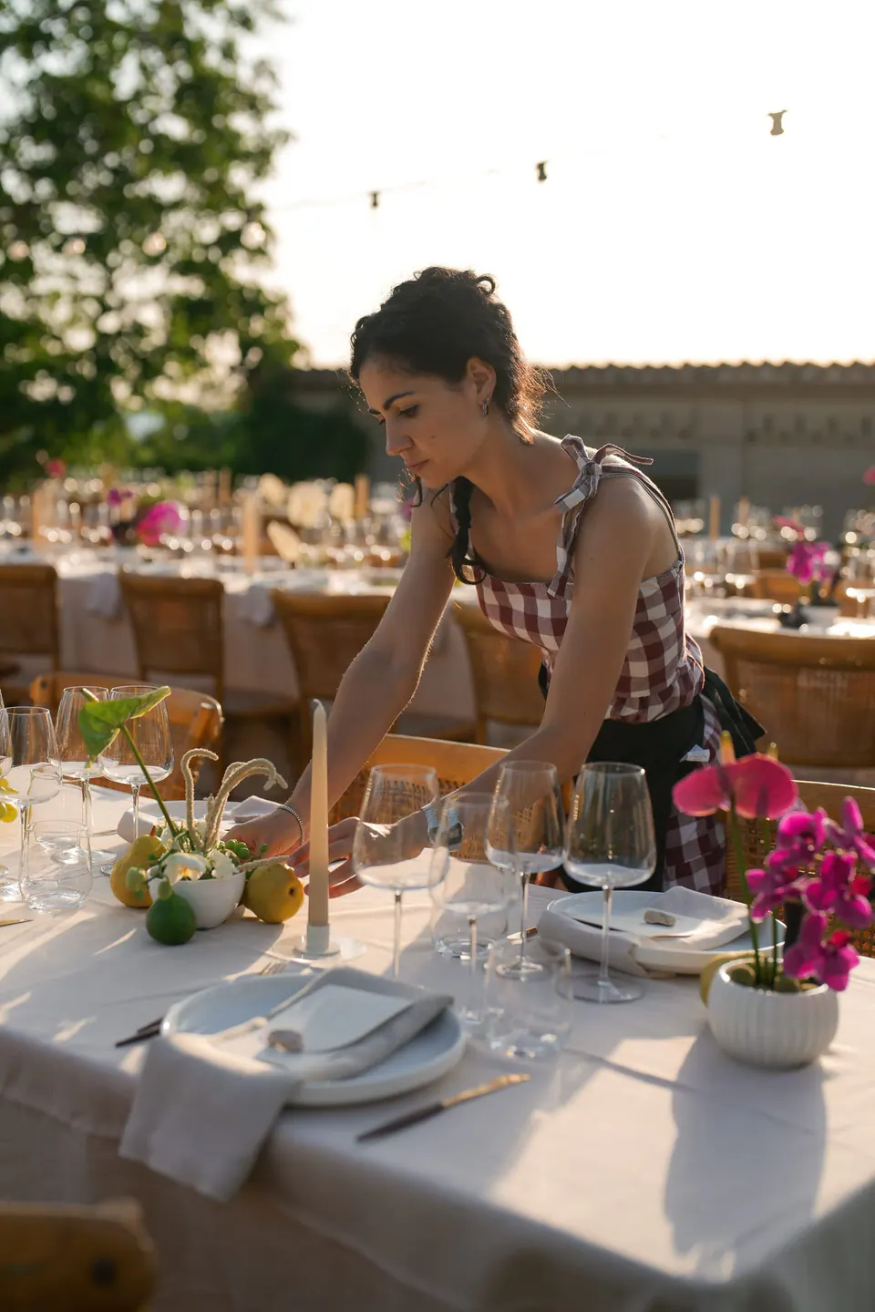 A guest leaning over a dinner table set with pink flowers