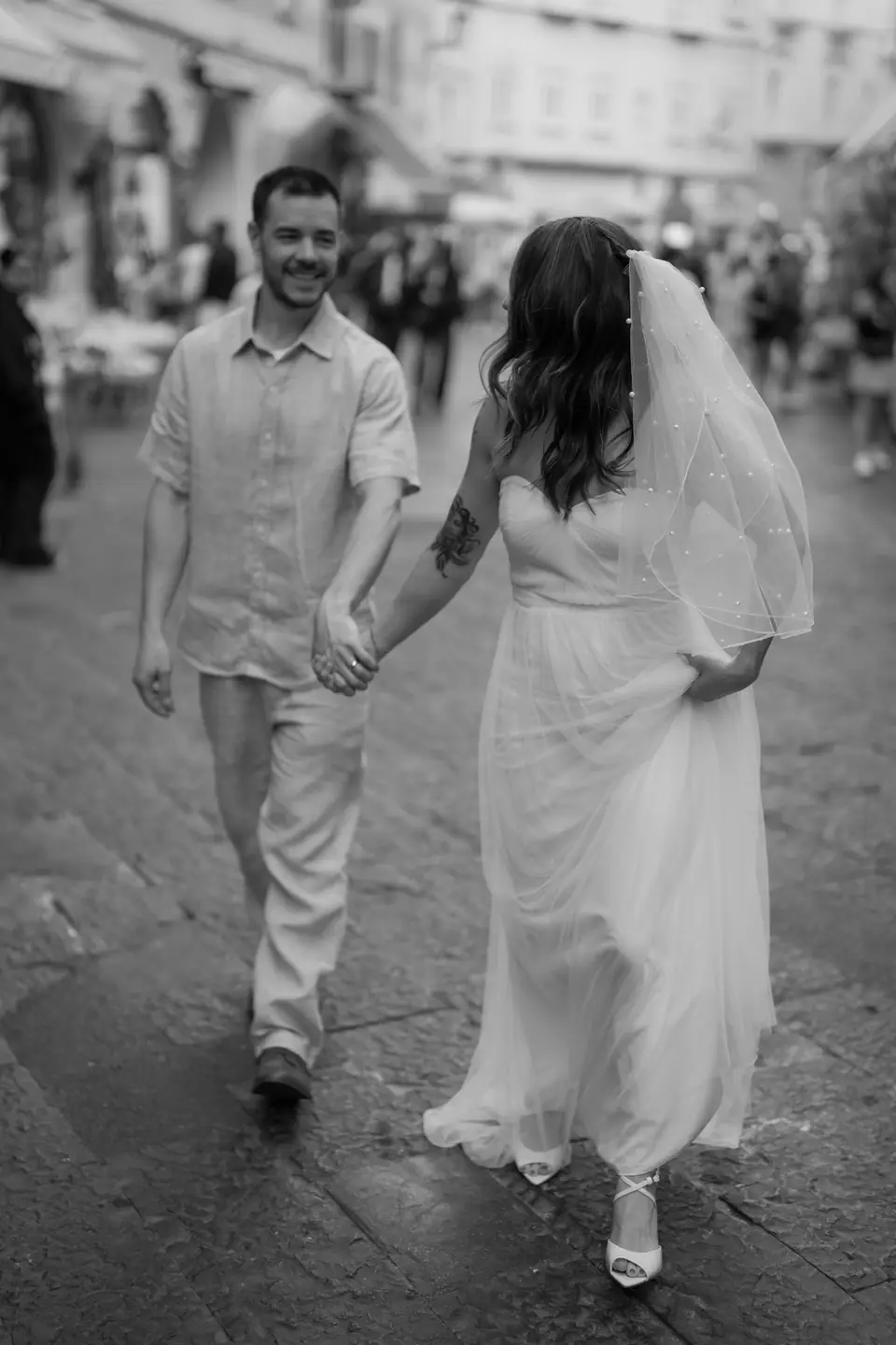 Black and white photo of the couple walking hand in hand through Piazza Duomo in Amalfi.