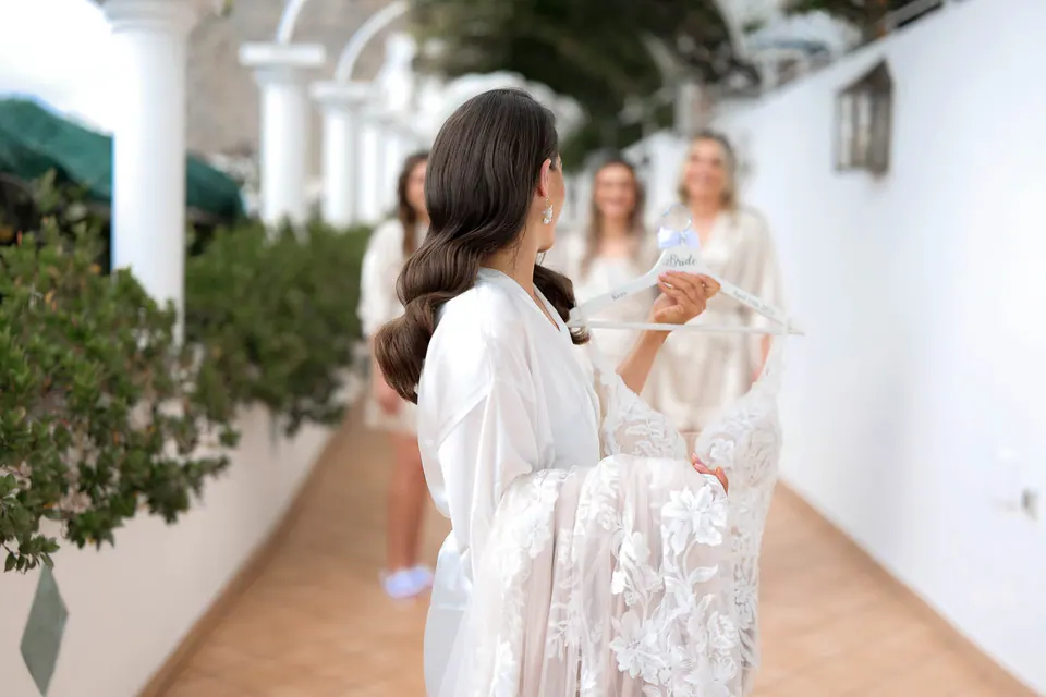 Sposa in vestaglia con le damigelle sulla terrazza assolata durante la mattina.