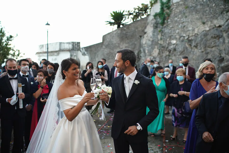 Bride and groom surrounded by guests on a stone lane after the ceremony.