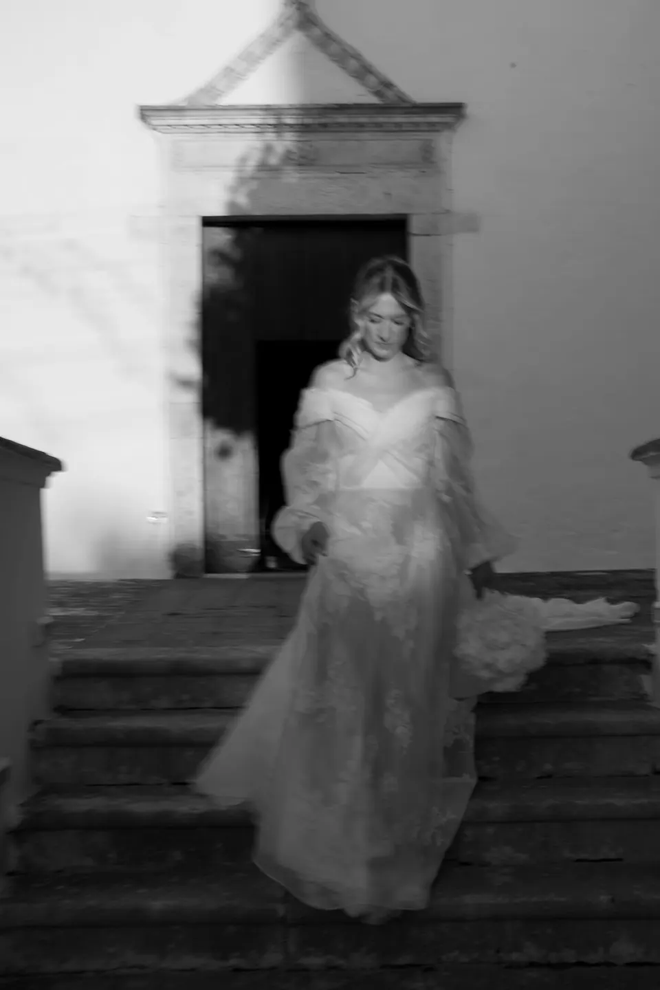Foto en blanco y negro de la novia bajando los escalones de la iglesia.