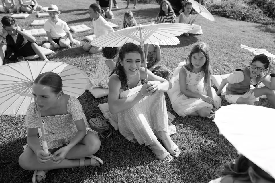Black and white photo of guests sitting on the grass with parasols
