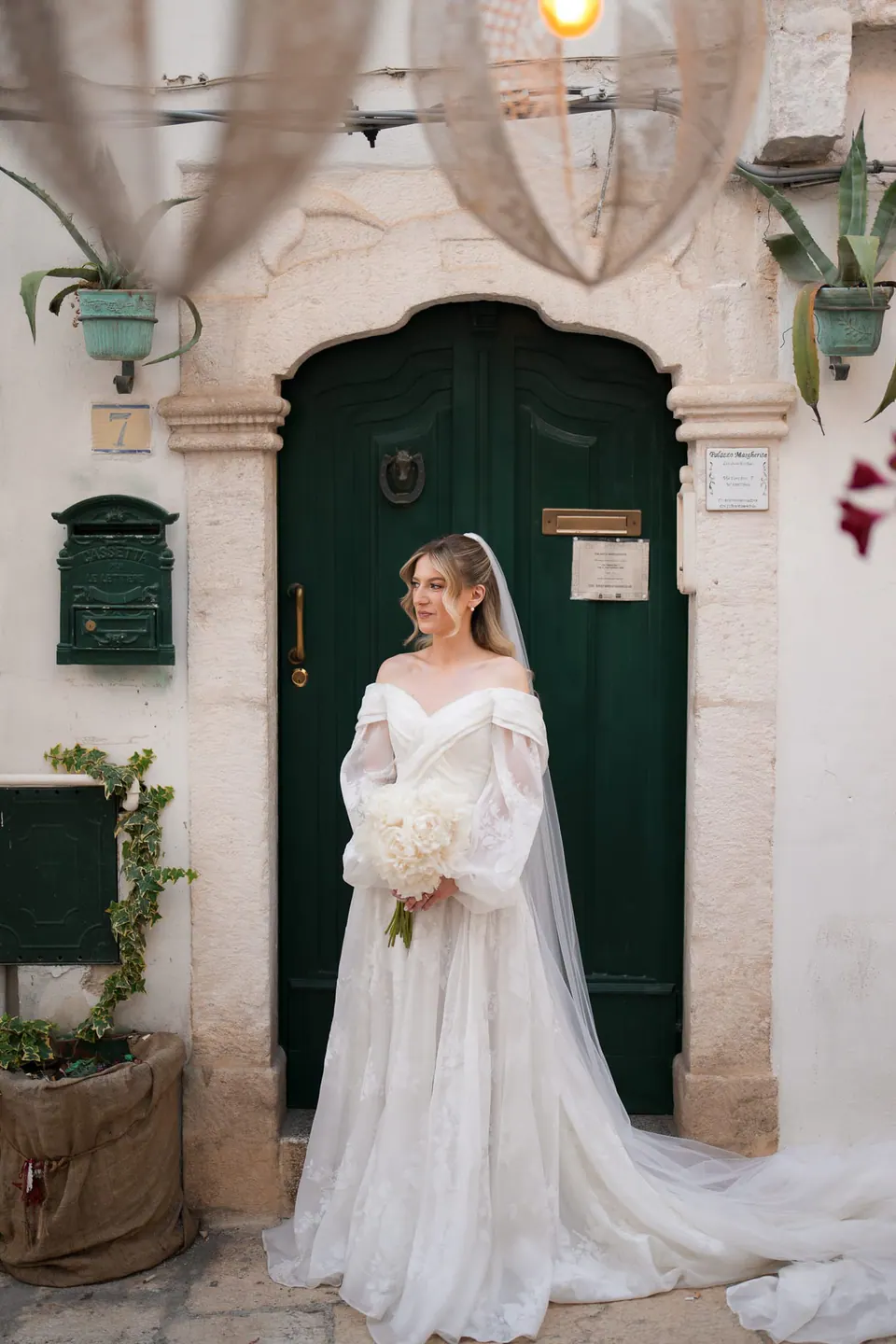 La novia delante de una vieja puerta verde en Ostuni.