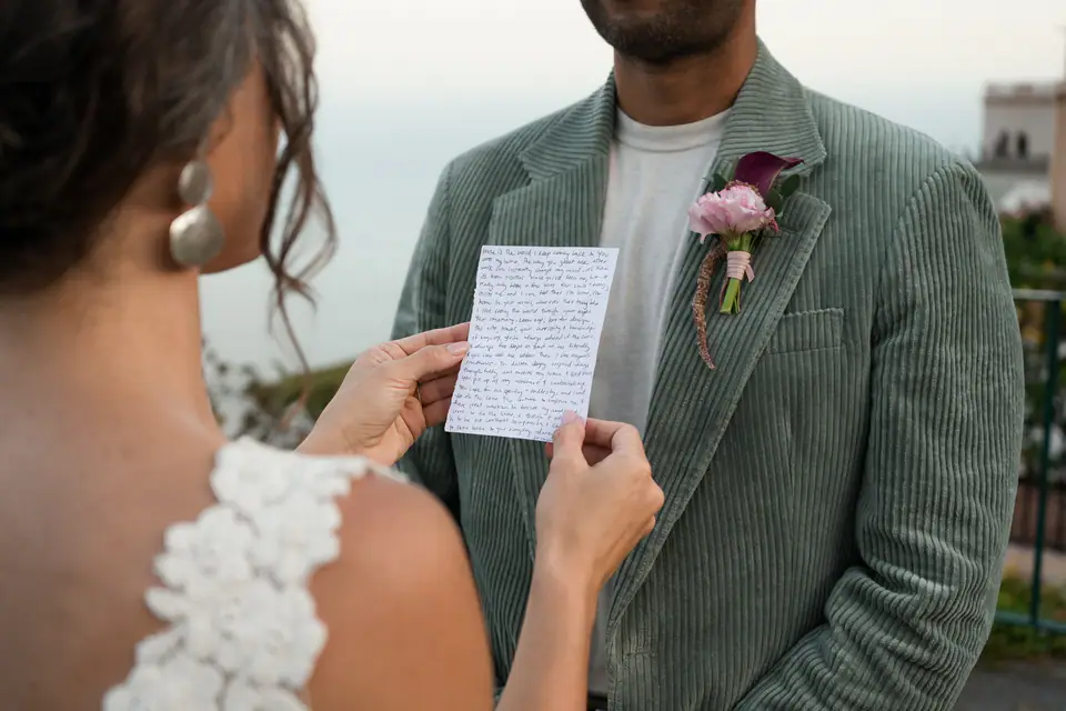 Close-up of the bride holding her vows as she reads them to the groom.
