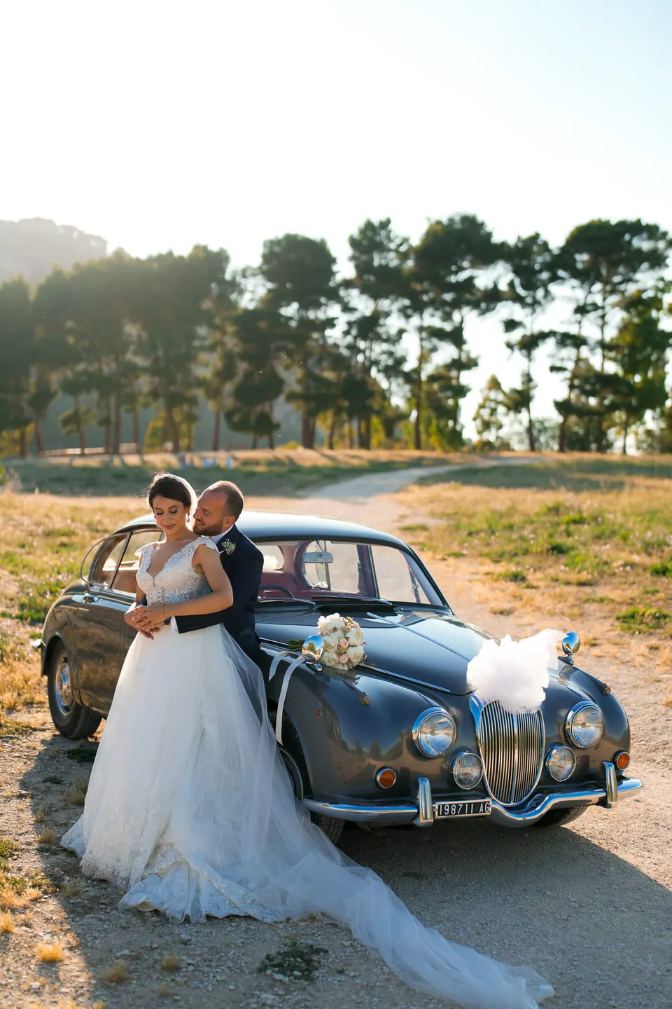 Bride and groom posing with vintage car, cinematic wedding photography Italy.