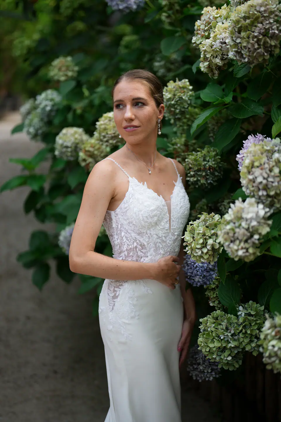 Bride among blue hydrangeas, looking away.