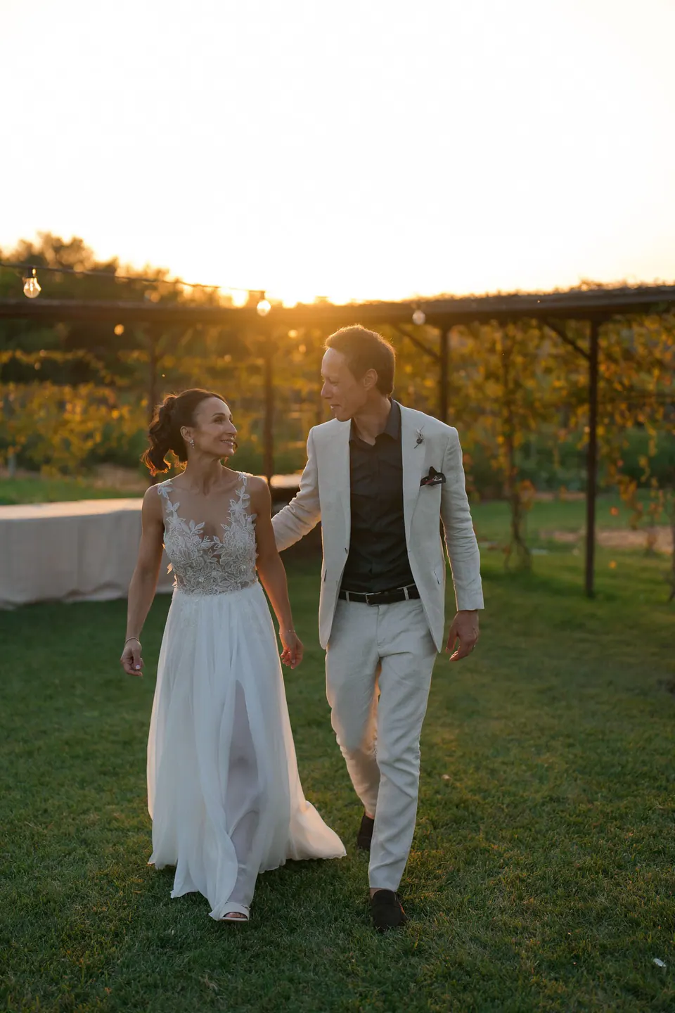 Bride and groom walking across the lawn at sunset