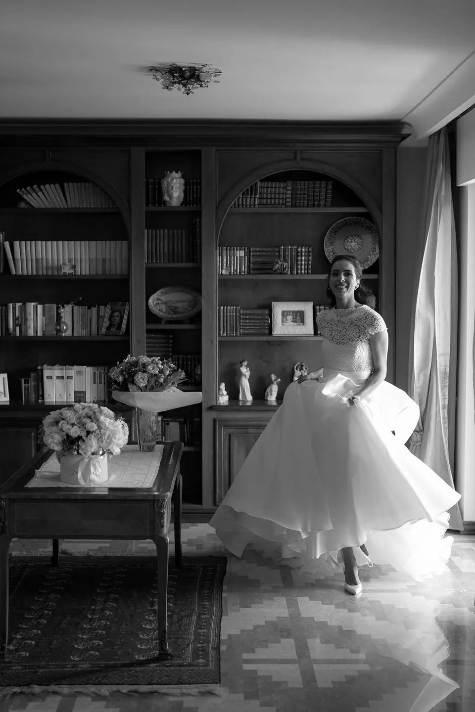Black and white photo of the bride twirling in a book-lined room