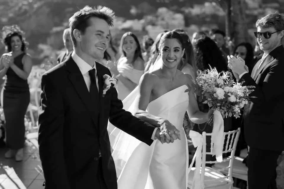 Black and white photo of the couple walking back up the aisle among guests.