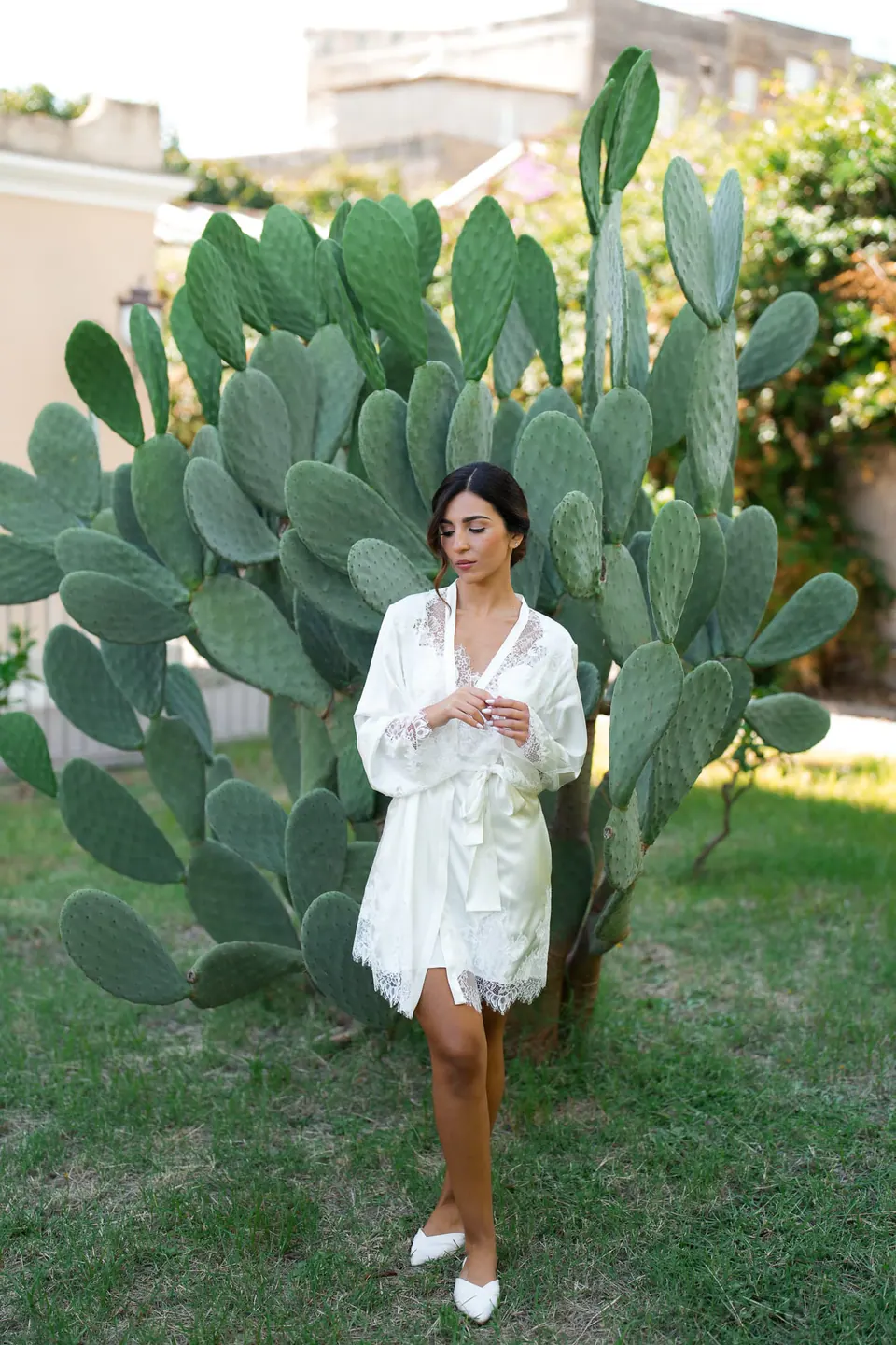 Bride in her robe next to a prickly pear cactus in the garden