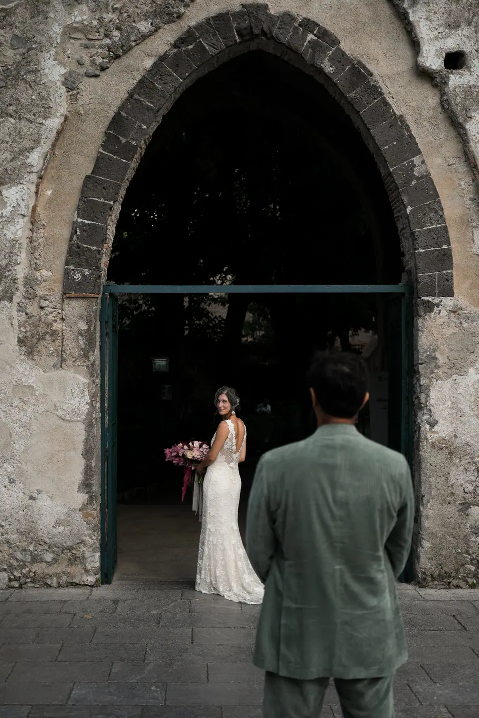 Bride and groom at the entrance of an old church with a gothic arch.