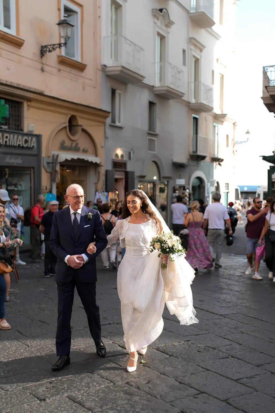 Father walking the bride through the streets of Amalfi, passers-by looking on.