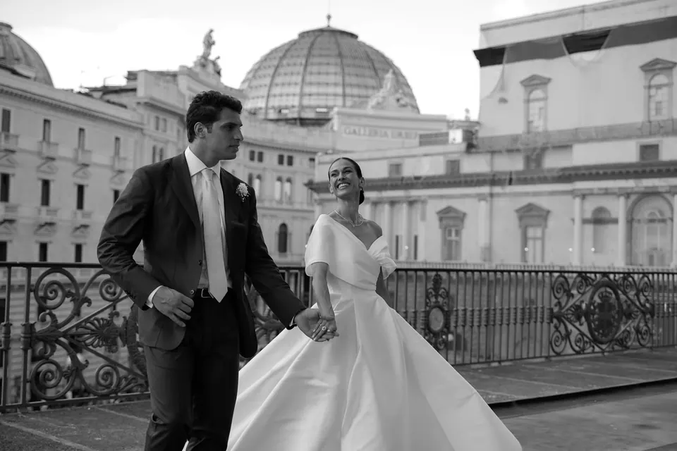 Foto in bianco e nero degli sposi su un balcone con la cupola di San Francesco di Paola.