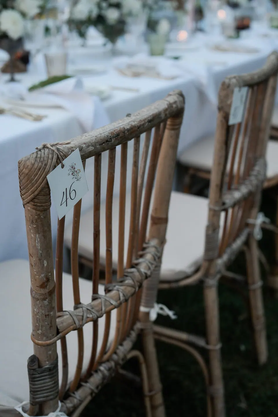 Detail of rustic wooden chairs and linen table settings for the dinner reception.